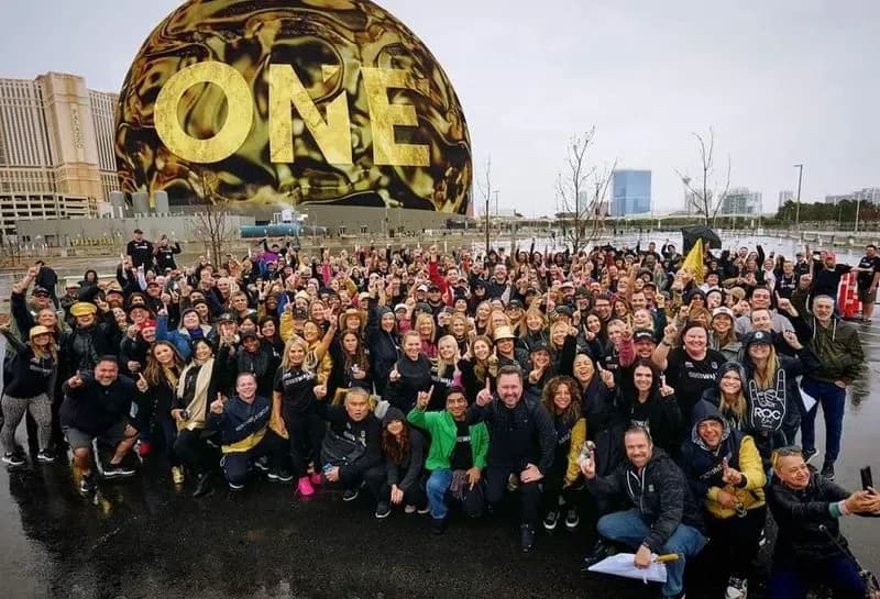 Realty ONE Group professionals gathered in front of the golden ONE sign