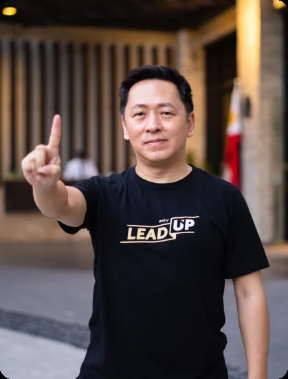 A broker in a LEAD UP shirt pointing to the camera