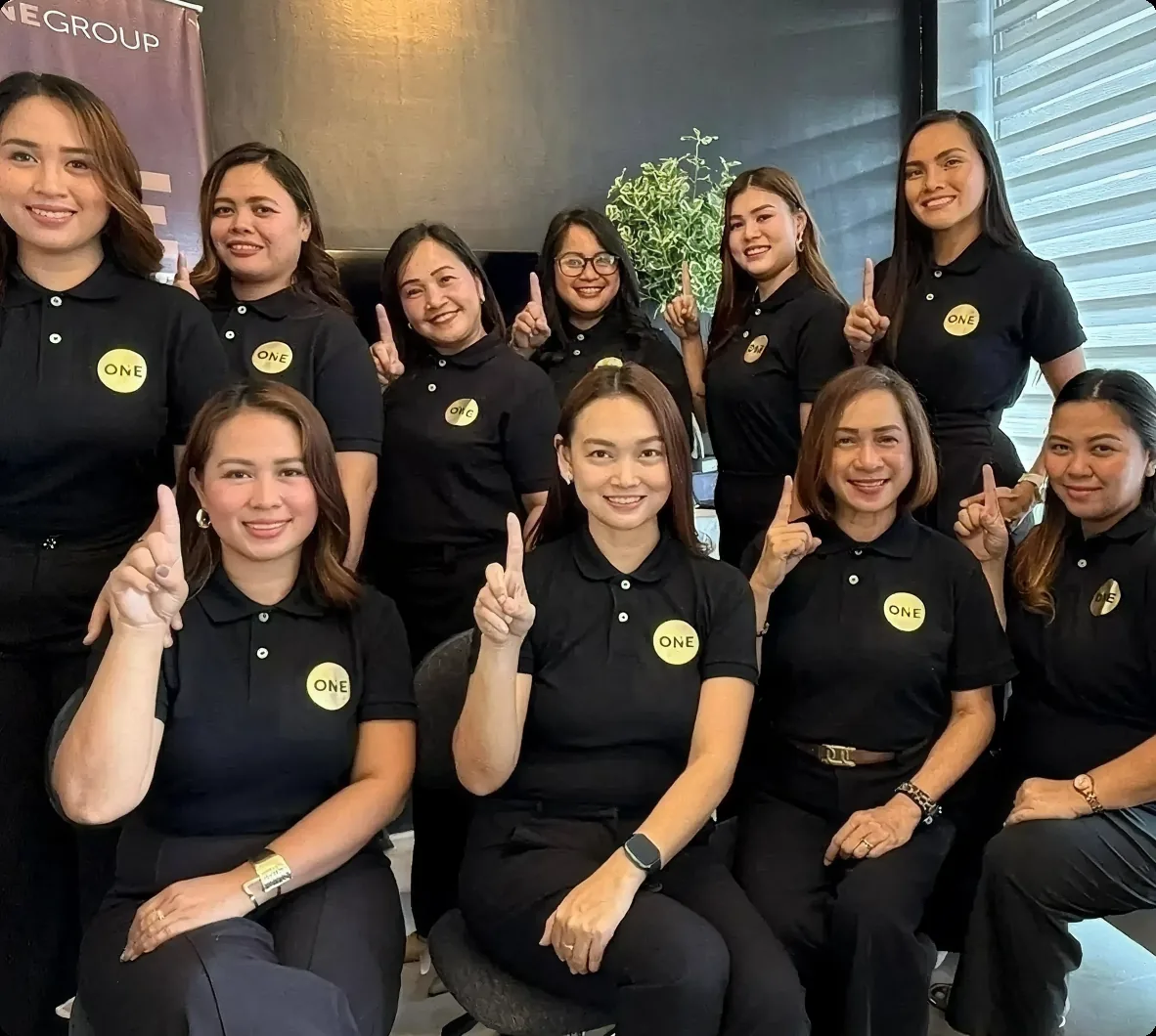 Realty ONE Group Philippines brokers in black polos holding up the ONE sign